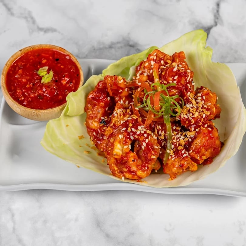 Indian chili shrimp with sesame seeds and green onions, served with a side of red chili sauce.